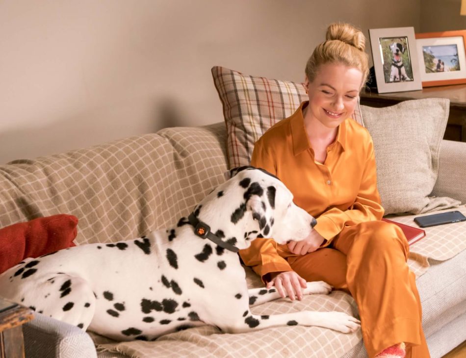 Woman in orange pyjamas sitting on sofa with a dalmatian