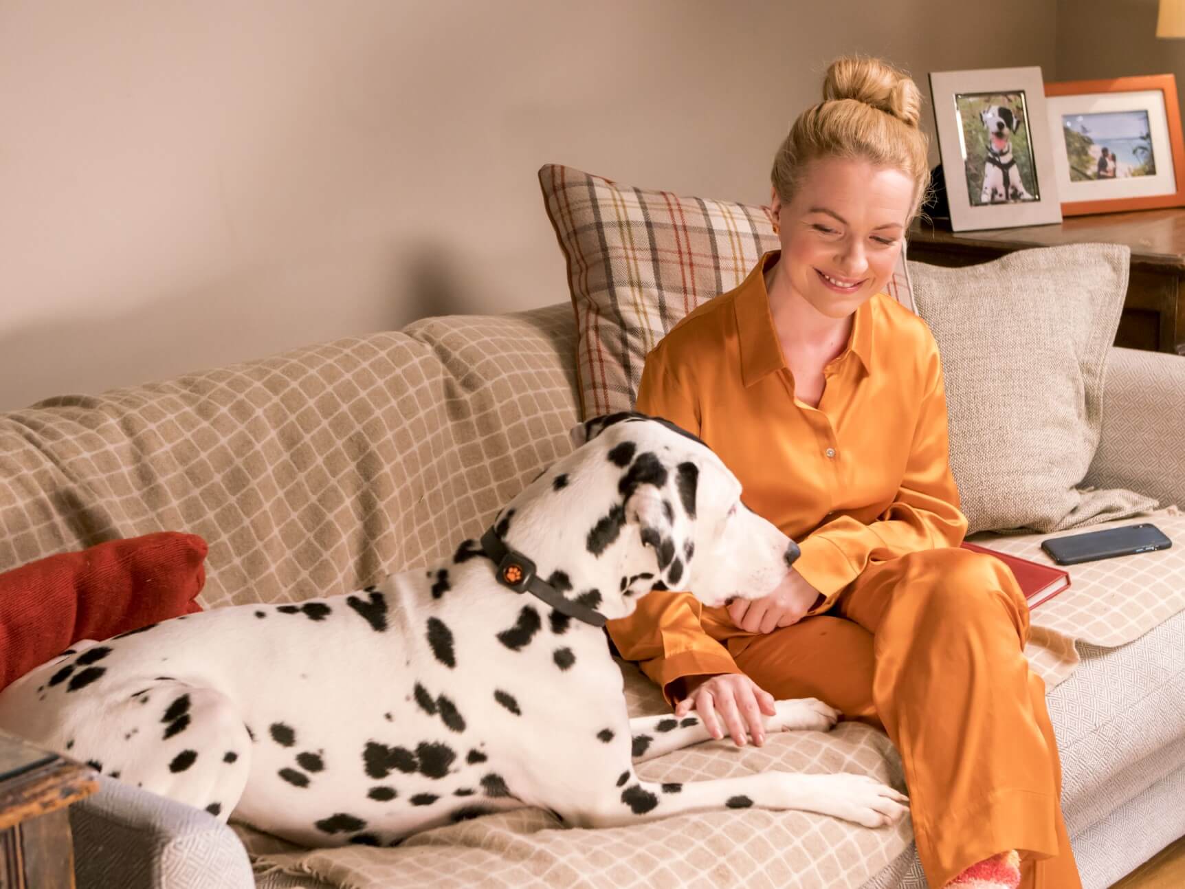 Woman in orange pyjamas sitting on sofa with a dalmatian