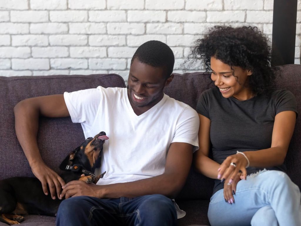 Man and woman sat on sofa with a dog