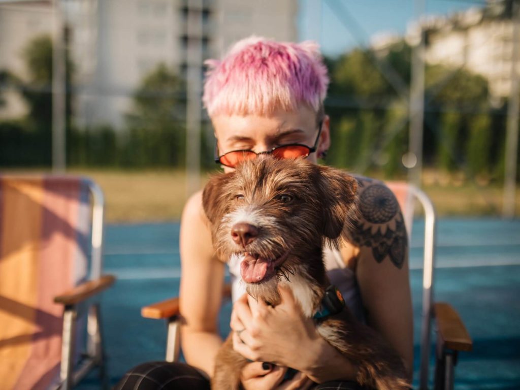 woman with pink hair cuddling a dog