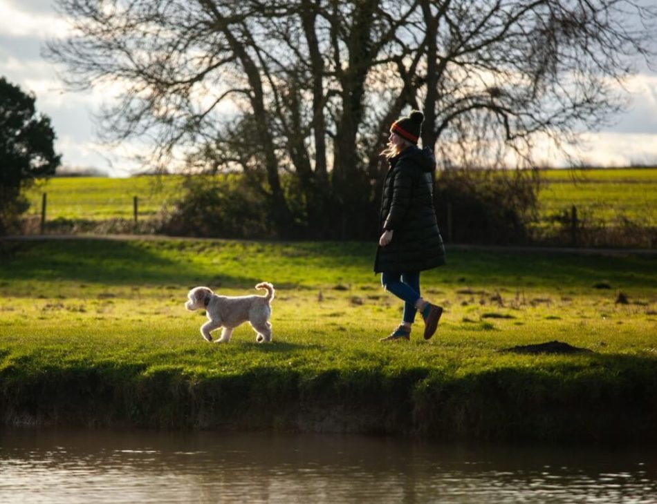 women walking cockapoo by the river