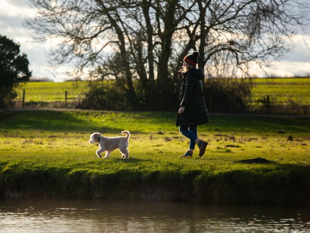 women walking cockapoo by the river